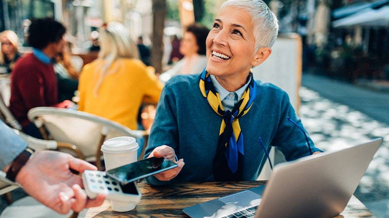 Woman paying for coffee using mobile phone